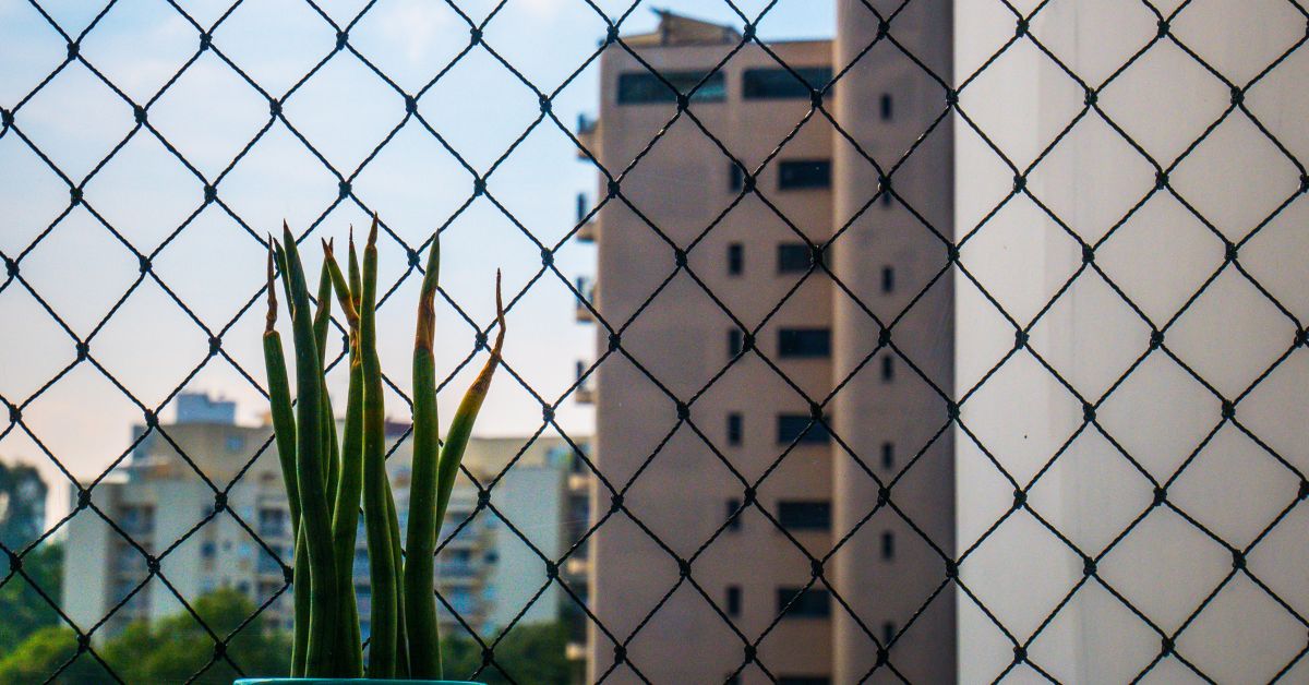Rede de proteção preta instalada em apartamento, com vista para a cidade